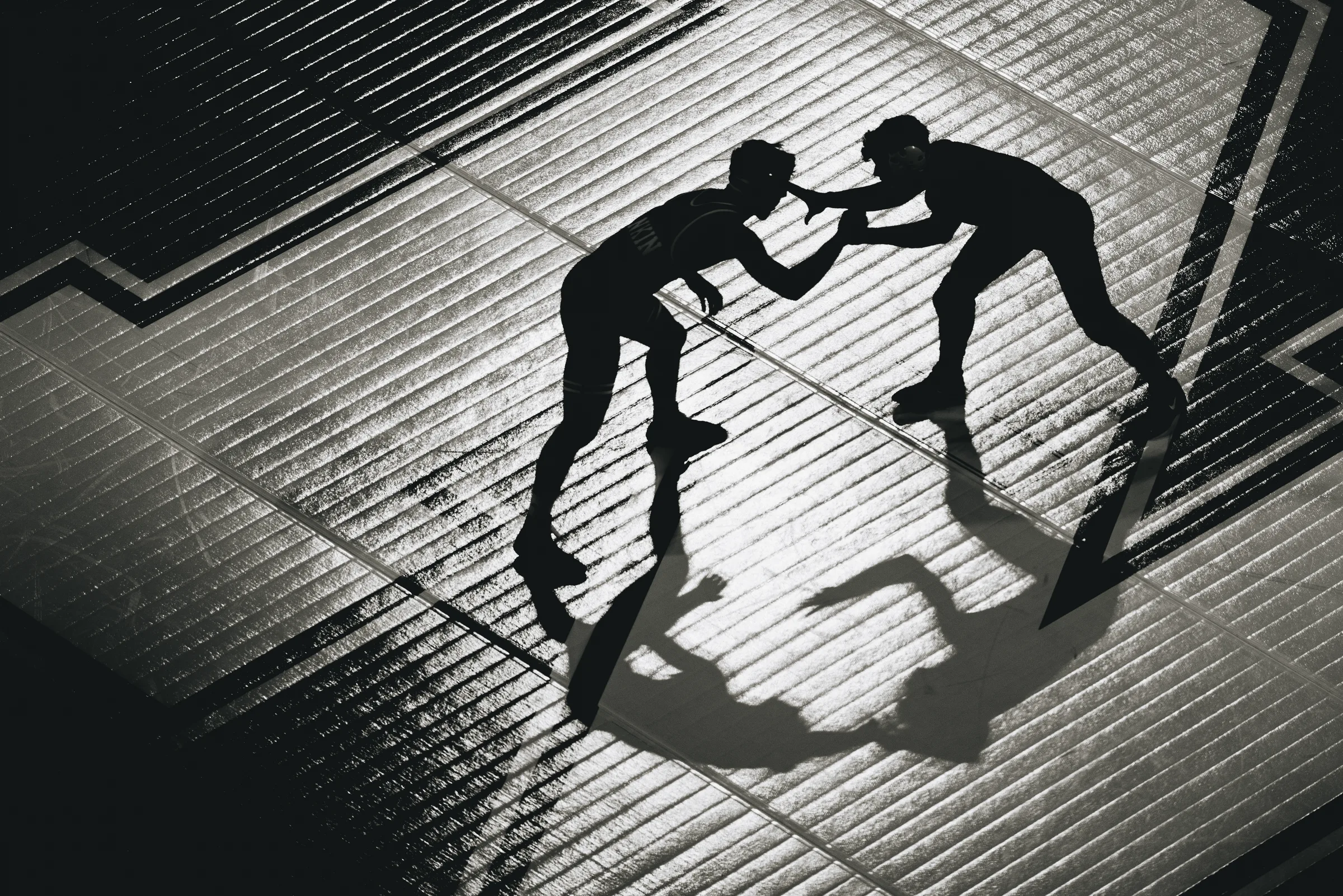 Two wrestlers grapple in silhouette on the mat at the Bob Devaney Sports Center during a dual against Army.