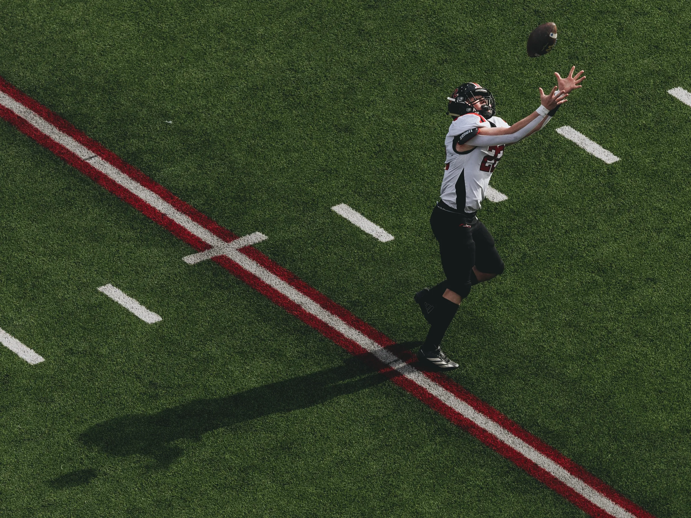 A receiver extends his arms to haul in a pass near the red zone during a Nebraska high school state football championship.