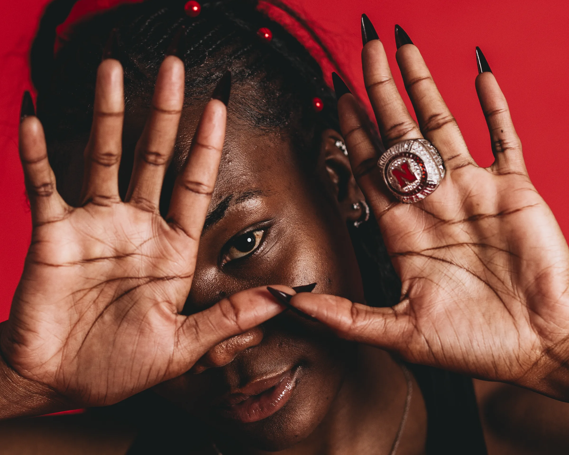 University of Nebraska track and field athlete Rhianna Phipps peers through her raised hands to display her Big Ten championship ring during a 2025 media day portrait session in Lincoln, Neb. Phipps, a five-time USTFCCCA All-American, won the Big Ten outdoor triple jump title in 2024 with a personal-best mark of 43 feet, 11 3/4 inches.