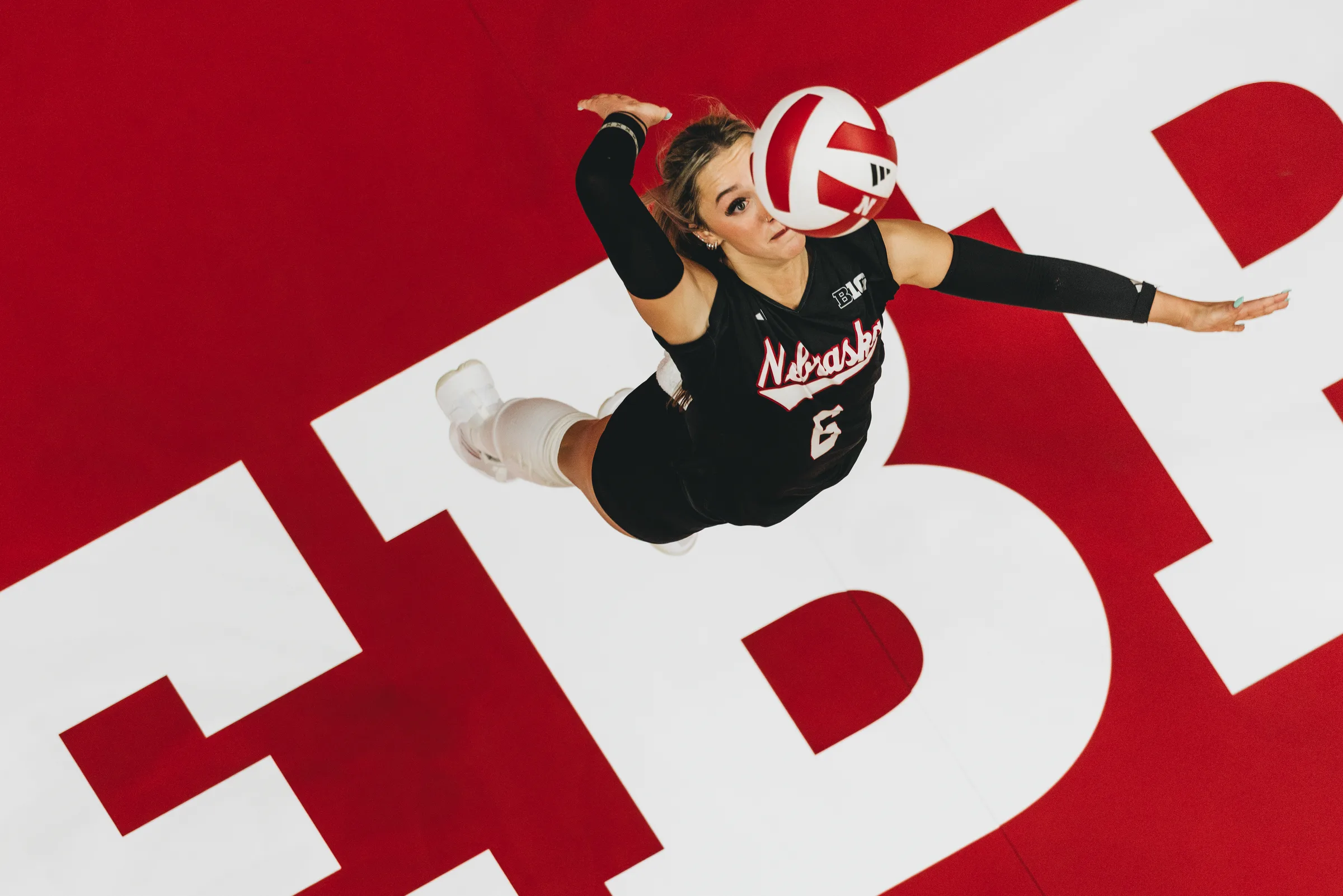 Nebraska Cornhuskers libero Laney Choboy launches a serve over the red-and-white court logo at the Bob Devaney Sports Center in Lincoln, Neb. Choboy, a defensive specialist, helped anchor the back row for the No. 2-ranked Huskers during their 2024 Big Ten season.