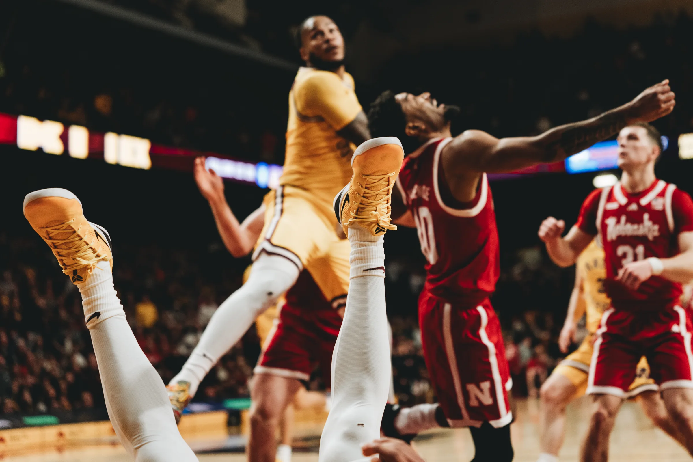 A Minnesota Golden Gophers player falls to the court as legs fly into the air during a game against ninth-ranked Nebraska.